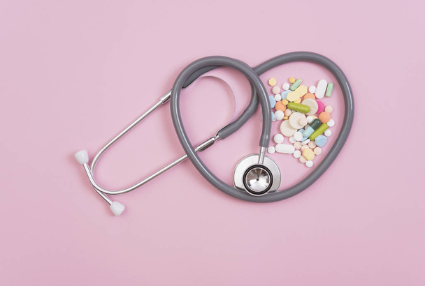 Stethoscoop en kleurrijke geneeskunde. Apotheek op roze achtergrond. - Foto, afbeelding