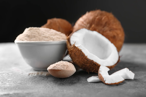 Bowl with coconut flour and fresh nuts on table - Φωτογραφία, εικόνα