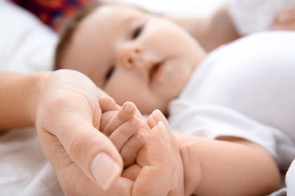 Baby holding mother's hand on bed - Fotoğraf, Görsel