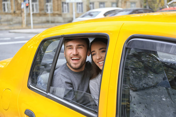 Happy νεαρό ζευγάρι στο πίσω κάθισμα του αυτοκινήτου ΤΑΞΙ - Φωτογραφία, εικόνα