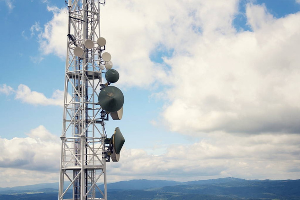 Κεραίες και πομπών στις τηλεπικοινωνίας πύργος με βουνά στο φόντο, θολό μπλε του ουρανού, ψηφιακή επικοινωνία και κρυπτογράφηση ασφάλεια έννοια - Φωτογραφία, εικόνα