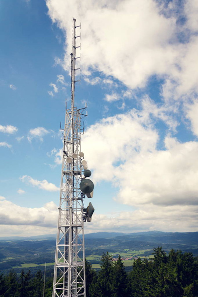 Aeriais e transmissores na torre de telecomunicações com montanhas no fundo, céu azul nublado, comunicação digital e conceito de segurança de criptografia
 - Foto, Imagem