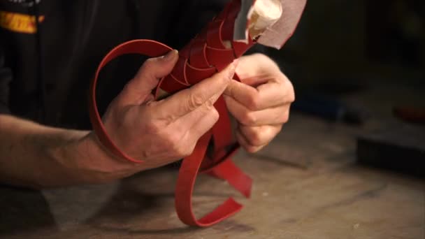Hands of working man, are holding red tube, weaving around it a leather case. - Footage, Video