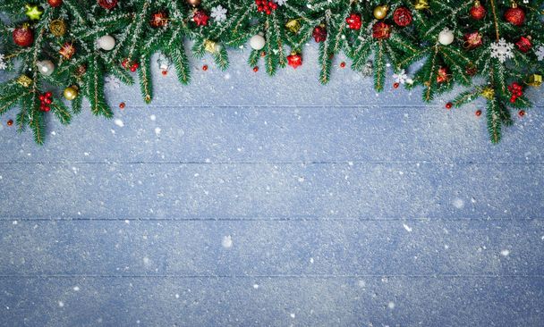 Отделения ели и рождественский орнамент на заснеженной голубой деревянной доске
 - Фото, изображение