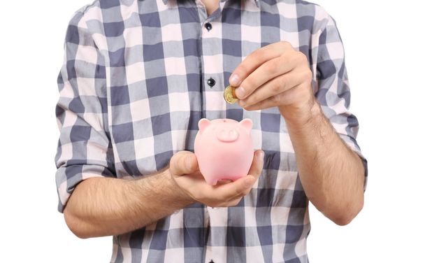 Young man putting coin into piggy bank on white background, closeup - Valokuva, kuva