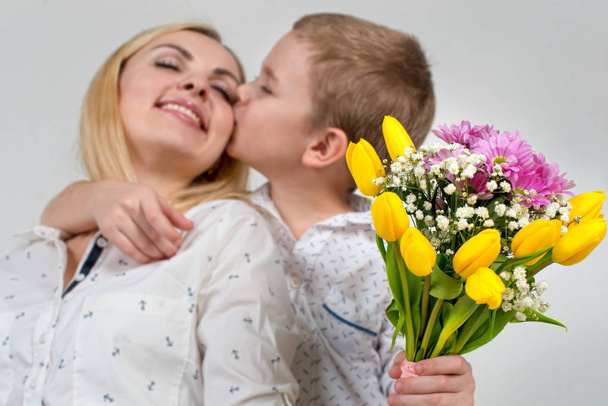 Son gives his beloved mother a beautiful bouquet of tulips.The concept of the celebration,women's day. - Фото, изображение