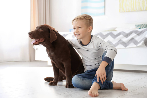 Cute little boy with dog on floor at home - Foto, Bild
