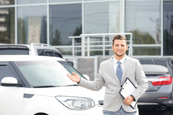 Salesman standing near new car outdoors - Фото, изображение