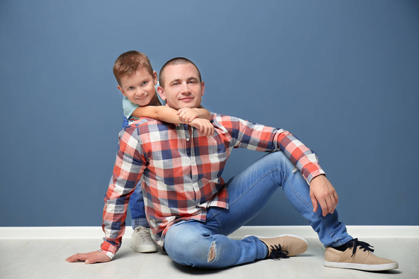 Dad and his son sitting on floor near color wall - Foto, Imagem