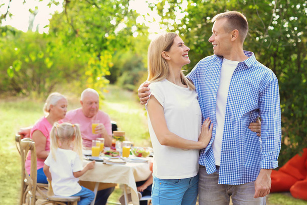 Happy couple with family having barbecue party outdoors - Photo, Image