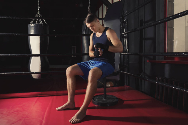 Boxeador masculino aplicando envolturas de mano
 - Foto, Imagen