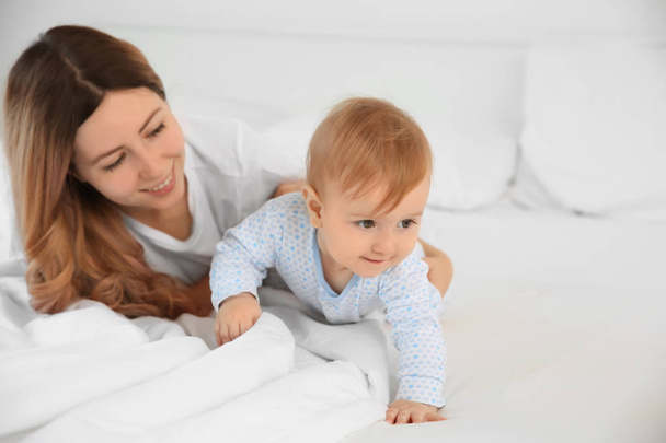 Young mother with baby on bed at home - Foto, Bild