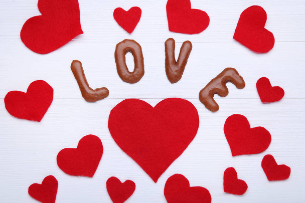 Love written by chocolate cookies alphabet with red hearts - Φωτογραφία, εικόνα