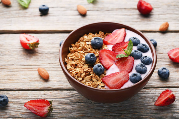 Tasty granola with berries in bowl on wooden table - Foto, Imagem