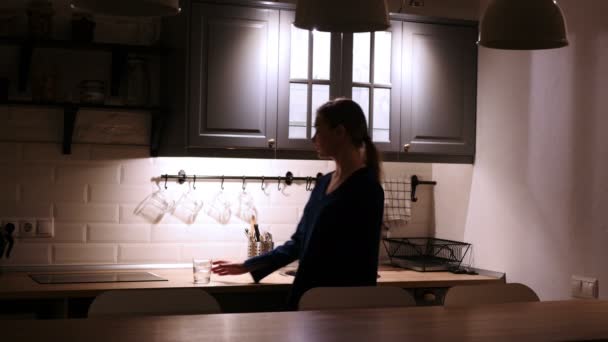 Frau kommt und trinkt nachts Wasser aus Glas in Küche - Filmmaterial, Video