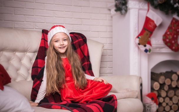 schönes Mädchen mit Weihnachtsmütze auf dem Sofa liegend, Studioaufnahme. - Foto, Bild