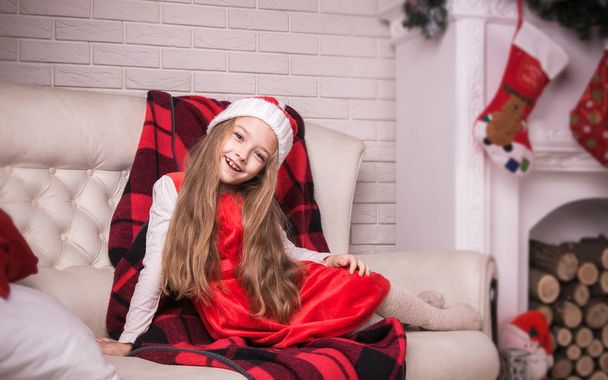 Lovely girl in santa cap lying on a sofa, studio shot. - Zdjęcie, obraz