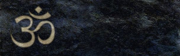 Golden Om kaiverrettu karkea musta kivi banneri tausta - vaalean kullan kaiverrettu OM symboli vasemmassa kulmassa vastaan jet musta kiiltävä märkä näyttää leveä kivimuuri
 - Valokuva, kuva
