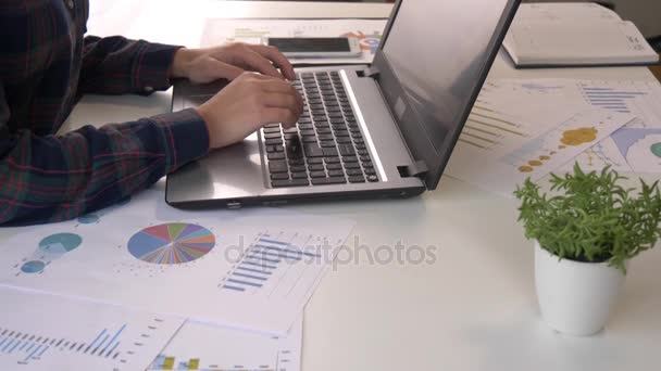 Genç kadın Finans Pazar Analisti tahta masada otururken dizüstü bilgisayarda ofisinde çalışıyor. İşadamı Finans grafikleri analiz. Grafikler ve diagramms - Video, Çekim