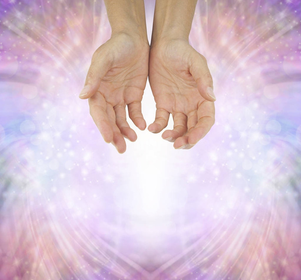 Kädet Humble Healer - naisten kädet auki cupped asentoon vaaleanpunainen kuohuviini energian muodostumista tausta kopio tilaa alla
 - Valokuva, kuva