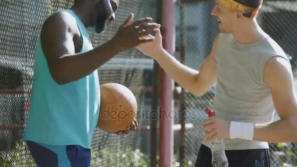 Two friends shaking hands, discussing basketball game strategy at stadium - Filmati, video
