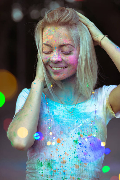 Elégedett szőke nő arcán pózol a col Holi festékkel - Fotó, kép