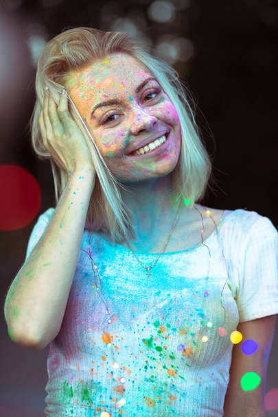 lustige blonde Frau mit Holi-Farbe im Gesicht posiert mit Farbe - Foto, Bild