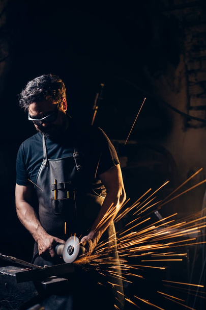 man Using Angle Grinder in Factory and throwing sparks - Foto, immagini