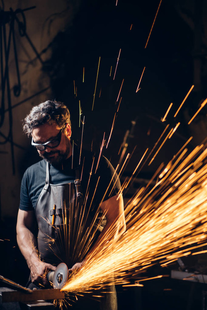 man Using Angle Grinder in Factory and throwing sparks - Fotoğraf, Görsel