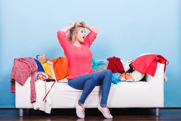 Woman does not know what to wear sitting on couch - Foto, imagen