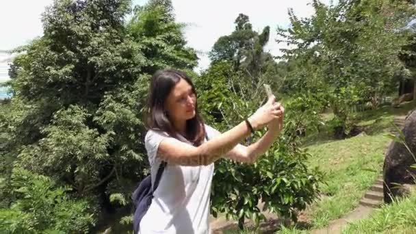 Jovem mulher fazendo selfie no parque com um smartphone
 - Filmagem, Vídeo
