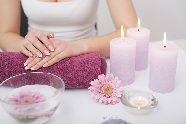 Beautiful manicure with orchid, candle and towel on the white wo - Photo, image