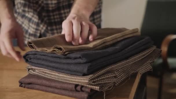 Wol kiest in de stack. Jonge man werken als een kleermaker en een naaimachine gebruiken in werkplaats. - Video