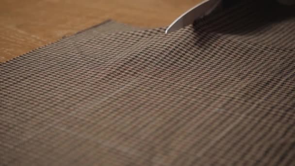 Closeup snijden bruine geruite wollen stof. het lijnpatroon. Jonge man werken als een kleermaker en een naaimachine gebruiken in werkplaats. - Video