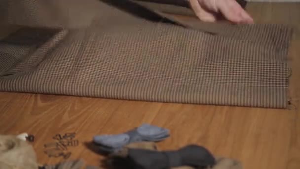 Vouw bruine geruite wollen stof. Jonge man werken als een kleermaker en een naaimachine gebruiken in werkplaats. - Video