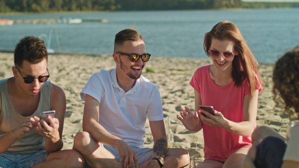 Молодые люди веселятся на пляже с помощью телефонов
 - Фото, изображение