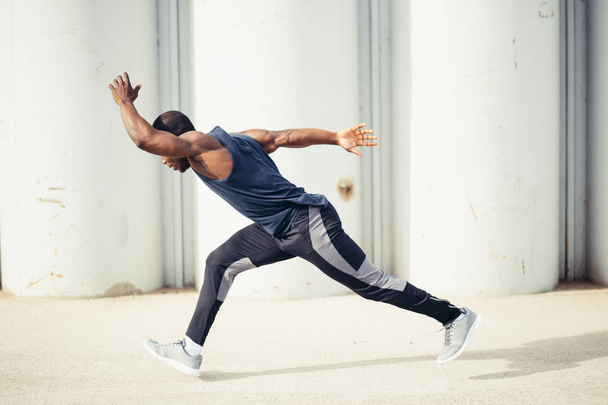 side view of cut Black athlete sprinting on the street. - Фото, изображение