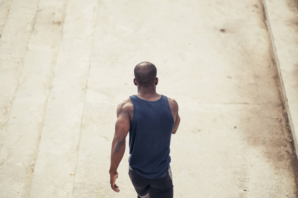 rear view. African runner runs along the stairs - Foto, Imagen