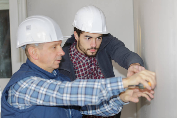 two working builders applies glue on a wall - Foto, Imagen