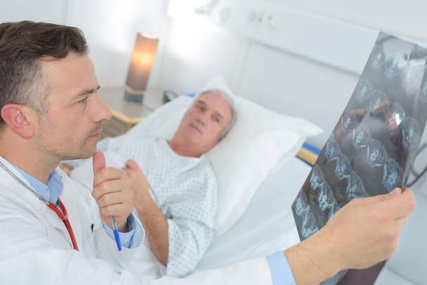 mature doctor examinating patients xray at the hospital - Foto, Bild