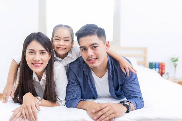 Aziatische en gelukkige familie liggend op een bed - Foto, afbeelding