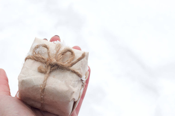 vista dall'alto mano donna in possesso di scatola regalo marrone per il nuovo anno sulla neve con spazio
. - Foto, immagini