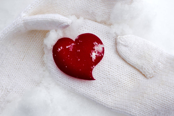 Heart in cozy arms on snow winter background - Photo, Image