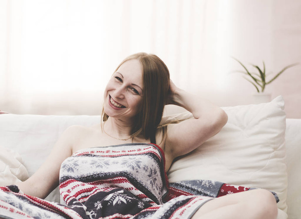 Beautiful girl on a white bed laughing after a shower in the winter. - Valokuva, kuva