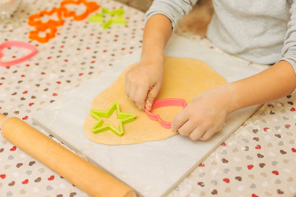 Mani di bambino in età prescolare che fanno biscotti utilizzando stampi per biscotti
 - Foto, immagini