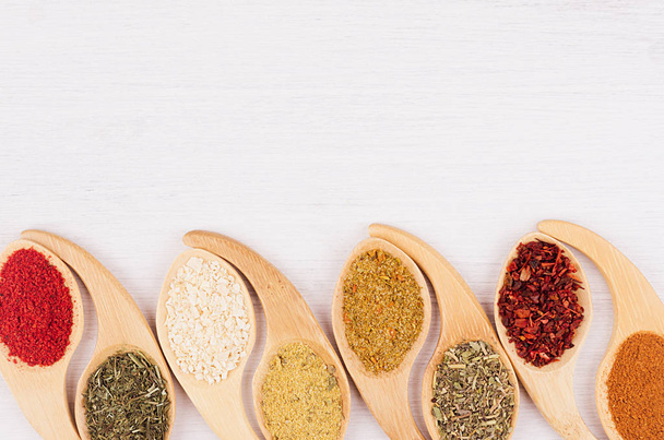 Multicolored asian spices in quaint spoons on white wooden background. Top view, closeup. - Foto, Imagem