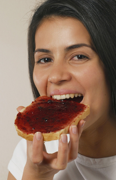 Nuori nainen syö marmeladia paahtoleipää
. - Valokuva, kuva