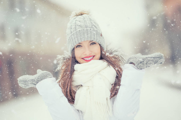 Beautiful smiling young woman in warm clothing. The concept of portrait in winter snowy weather - Foto, Bild