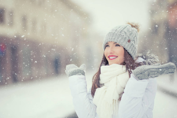 schöne lächelnde junge Frau in warmer Kleidung. das Konzept des Porträts bei winterlich schneebedecktem Wetter - Foto, Bild