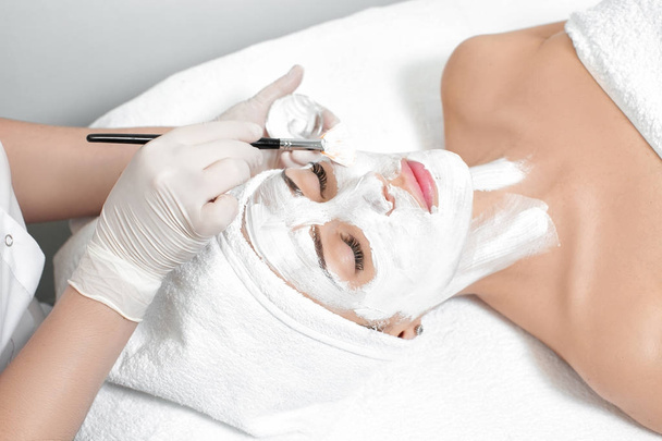 косметолог наносит маску на лицо женщины
 - Фото, изображение